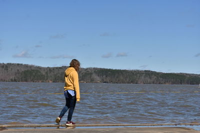 Rear view of man standing at beach against sky