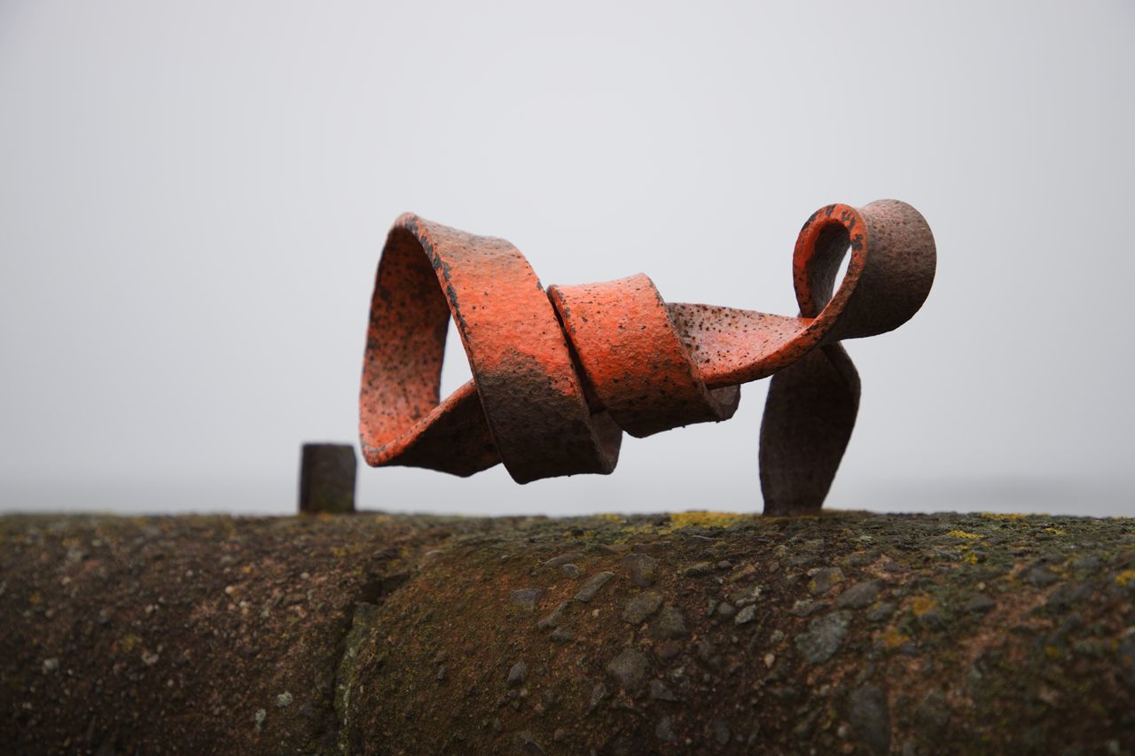 CLOSE-UP OF RUSTY METAL AGAINST ROCK