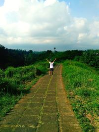 Rear view of person standing on field against sky