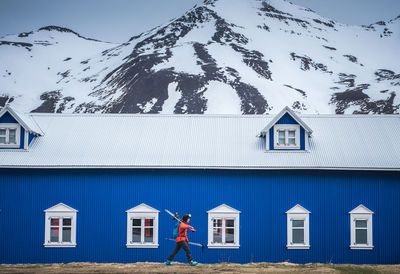 A woman walks in front of a blue building in iceland