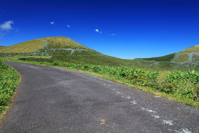 Road by mountains against clear blue sky