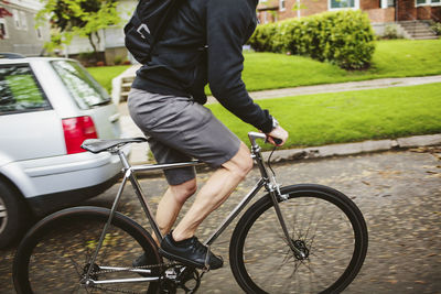 Low section of male commuter riding bicycle on street