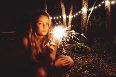 Happy girl holding sparkler at night