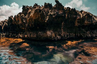 Rock formations in water against sky