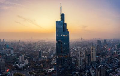 Modern buildings in city against sky during sunset