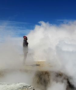 Full length of woman standing on active geyser against sky