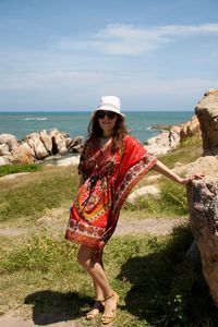 Young woman standing at beach against sky