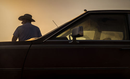 Side view of man standing in car