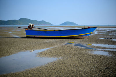 Boat moored on beach against clear sky