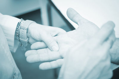 Midsection of doctor holding patient injured finger at hospital