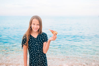 Portrait of smiling young woman standing on beach