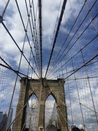 Low angle view of suspension bridge against cloudy sky