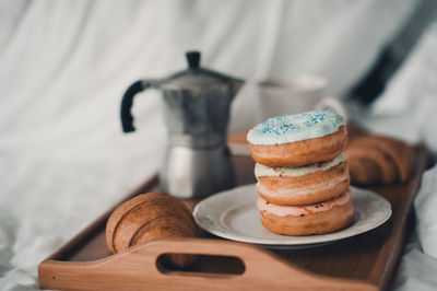 Morning coffee with glazed donuts and croissant on wooden tray in bed. tasty breakfast. 