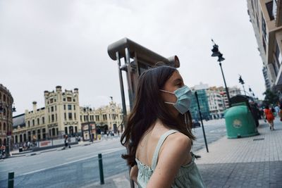 Woman standing on street in city against sky