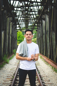 Portrait of young man standing on railroad track