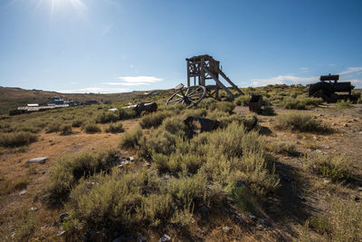 Scenic view of land with old gold mining equipment against sky