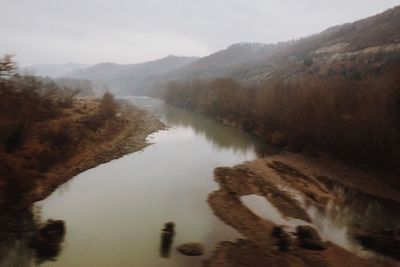 Scenic view of lake by mountains against sky
