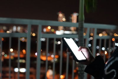 Midsection of man using mobile phone at night