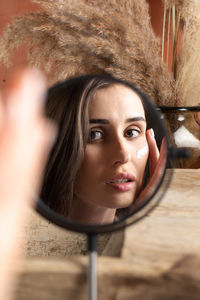 A young woman in front of a mirror applies a moisturizer on her face. beauty portrait