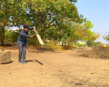 Full length of man holding cricket bat while playing on land