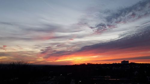 Silhouette buildings against dramatic sky during sunset