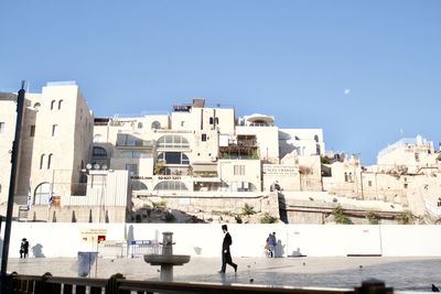 People walking in city against clear sky