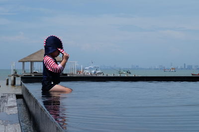 Woman by sea against sky