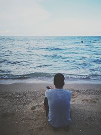 Rear view of man sitting on beach