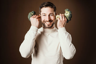 Portrait of young man standing against black background