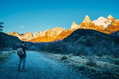 Rear view of man standing on rock against sky