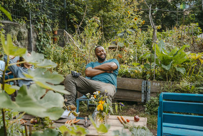 Young male environmentalist with arms crossed looking away in urban farm