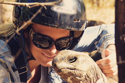 Close-up of young woman by giant tortoise on sunny day