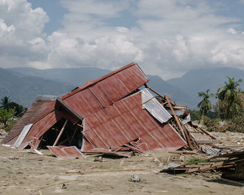 Damaged building on field against sky