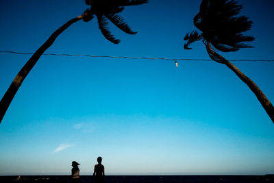 Low angle view of men against blue sky