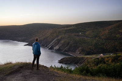 Rear view of man looking at mountains against sky