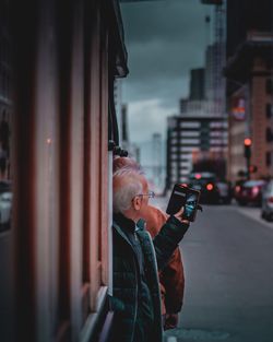 Side view of man using mobile phone in city