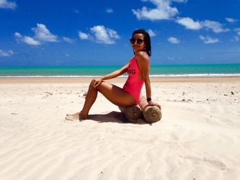 Portrait of woman sitting on wooden post at beach