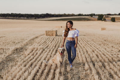 Mid adult woman with dog on agricultural field