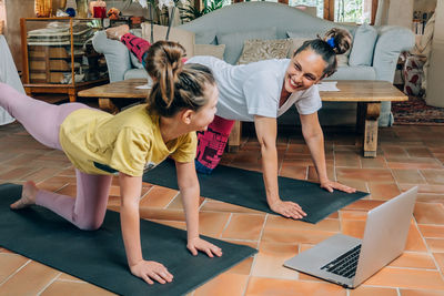 Full length of mother and daughter sitting on floor at home