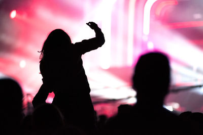 Rear view of silhouette of crowd with arms outstretched at concert. summer music festival concept