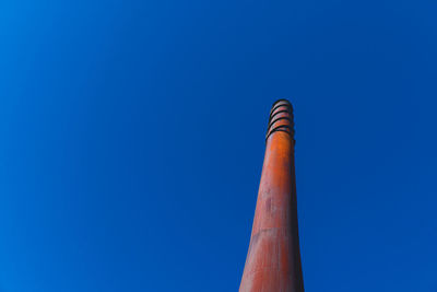 Low angle view of smoke stack against blue sky