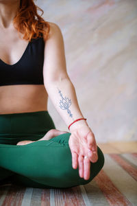 Midsection of woman sitting on floor at home