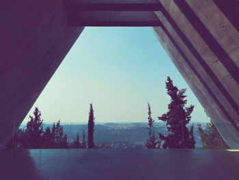 Trees and buildings against clear sky seen through window