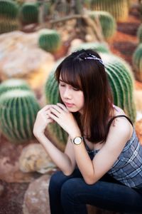 High angle view of woman sitting against cacti on field