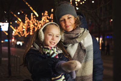 Portrait of smiling young woman with son in christmas tree during winter