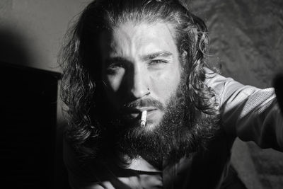 Close-up portrait of man smoking cigarette at home