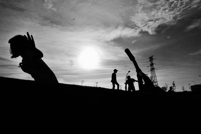 Low angle view of silhouette children playing against sky during sunset