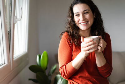 Portrait of young woman using mobile phone at home