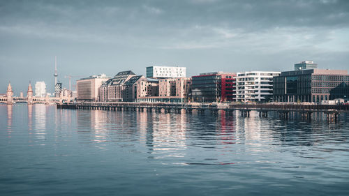 Sea by cityscape against sky