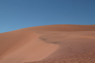 Scenic view of desert against clear blue sky